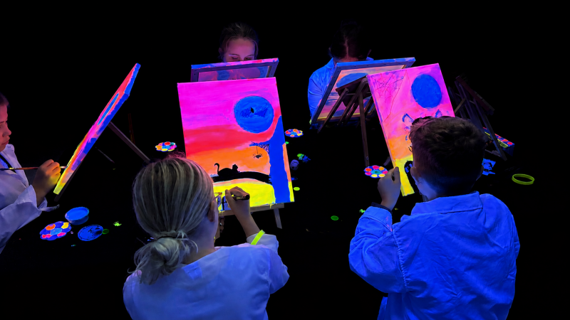 Kinder malen mit leuchtenden Neonfarben auf Leinwänden beim Geburtstagsevent im KUN5T Atelier Eschenbach SG.