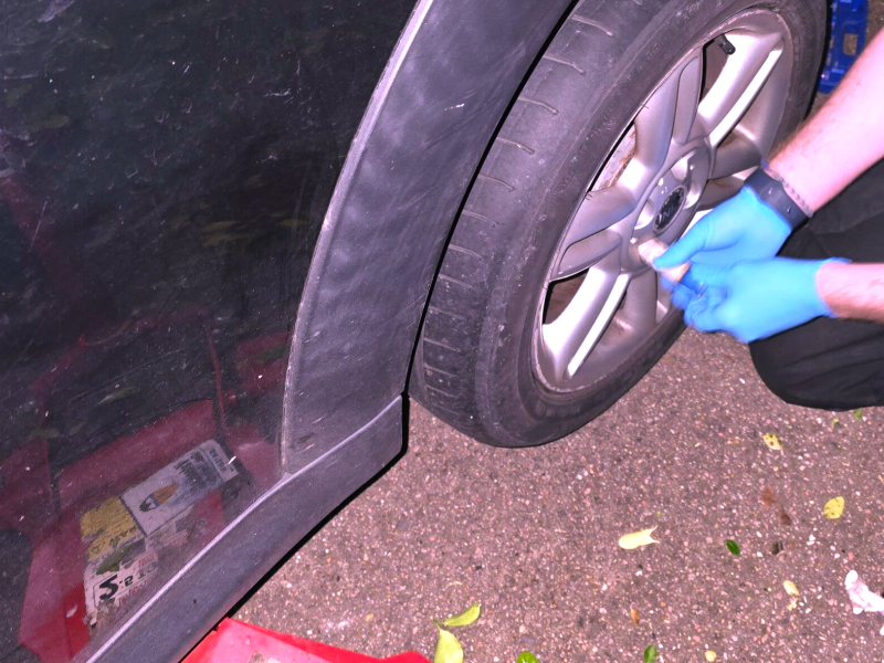 Mobile locking wheel nut removal being carried out on a car wheel using specialist equipment.