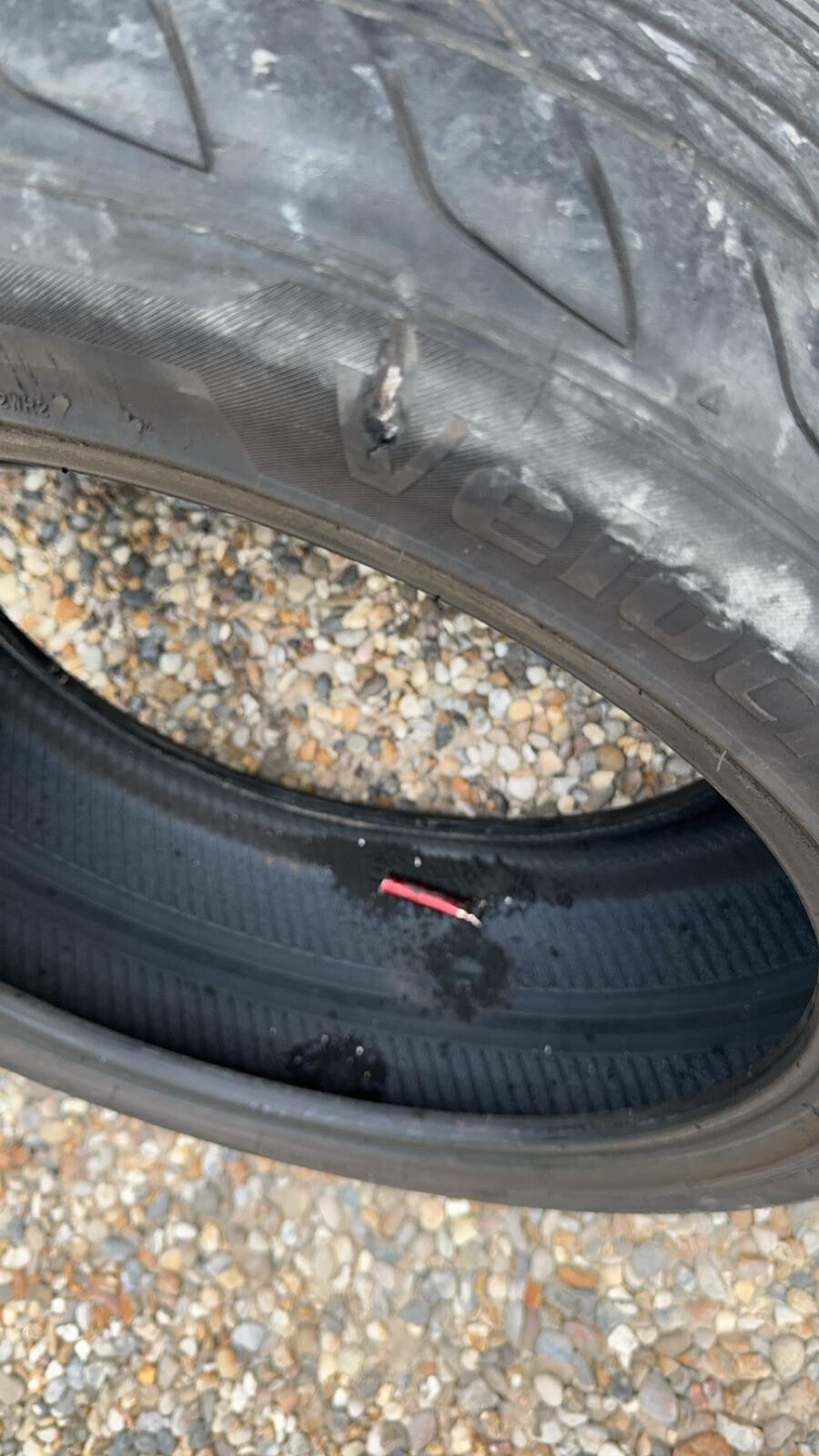 Car tyre sidewall punctured by a vape, showing damage caused by a foreign object.