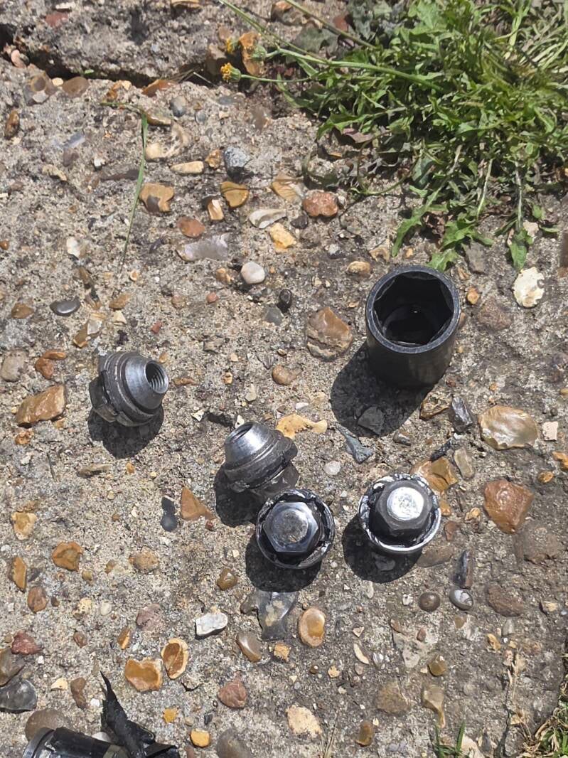 Removed locking wheel nuts and specialist extraction socket used during mobile locking wheel nut removal.