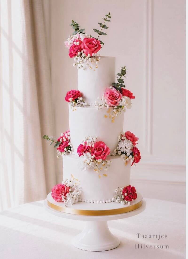 Prachtige romantische bruidstaart met roze en witte bloemen en met een beetje bladgoud 