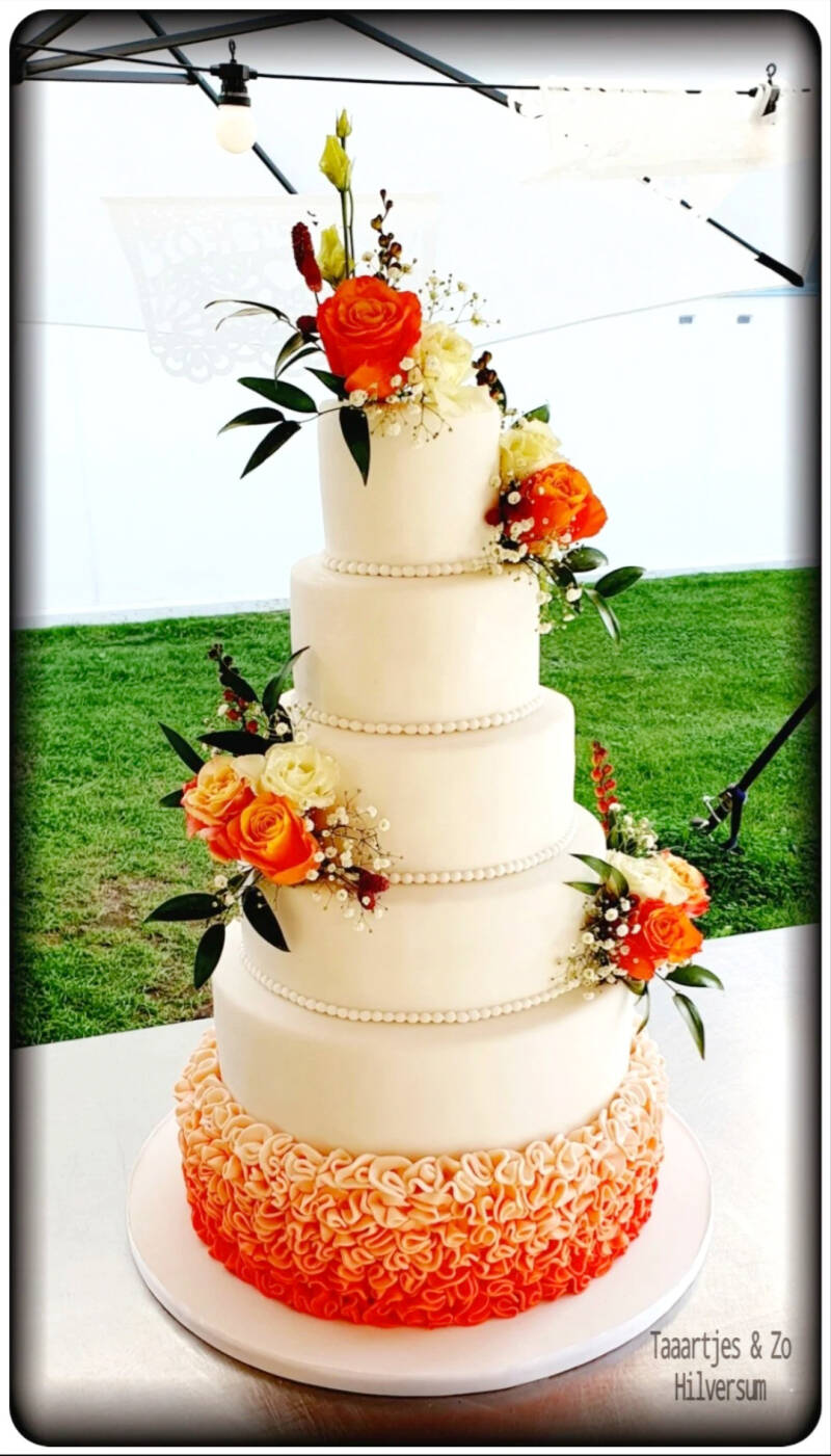 Grote bruidstaart met oranje ombre ruffles en echte bloemen Zonnestraal Hilversum