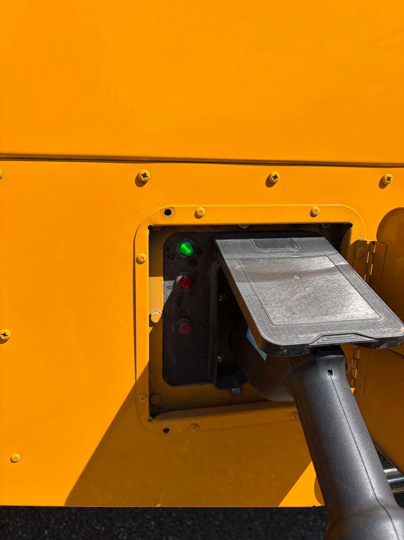 Close-up of an EV charging connector attached to an electric school bus