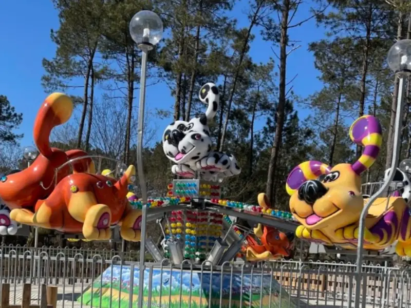 Manège pour enfants à Walygator Sud‑Ouest, parc d’attractions du Lot‑et‑Garonne, chiens colorés et décor festif.