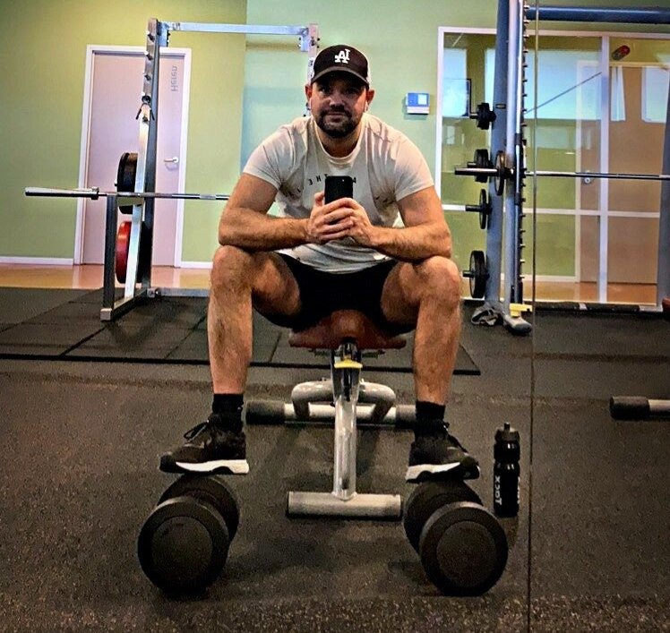 Man zittend in sportschool met dumbbells, krachttraining