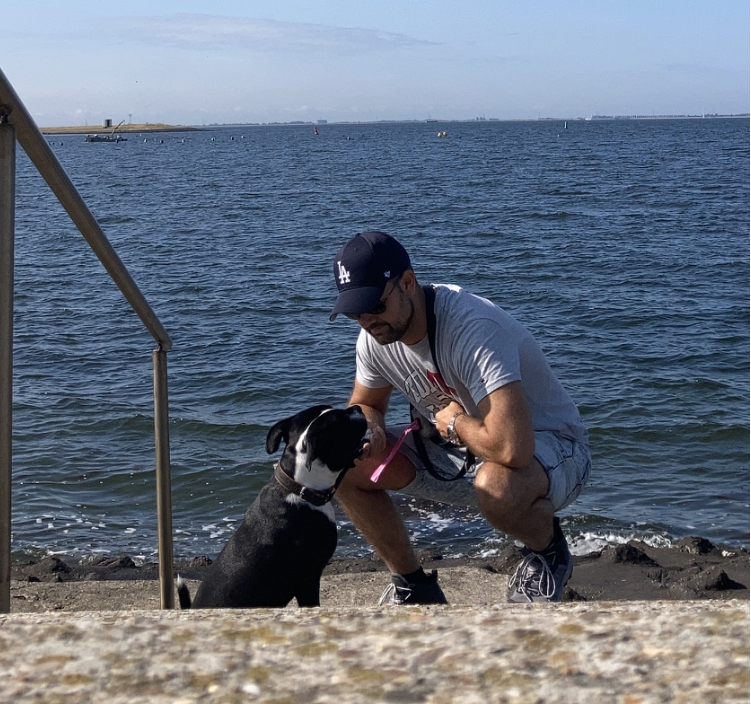 Man met hond bij de zee, genietend van een wandeling langs het water