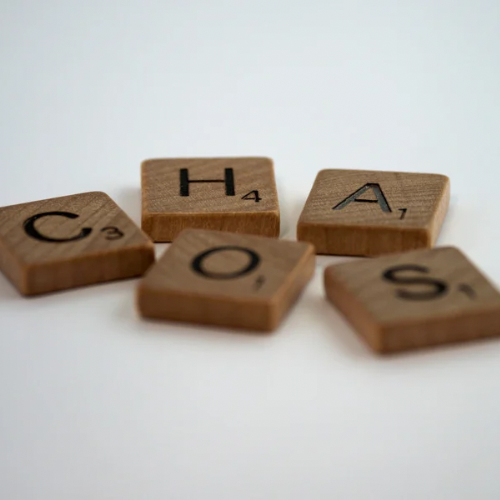 Scrabble-steentjes die het woord ‘Chaos’ vormen, gebruikt als banner voor een blog over overprikkeling. De afbeelding symboliseert de mentale druk en wanorde die overprikkeling kan veroorzaken.