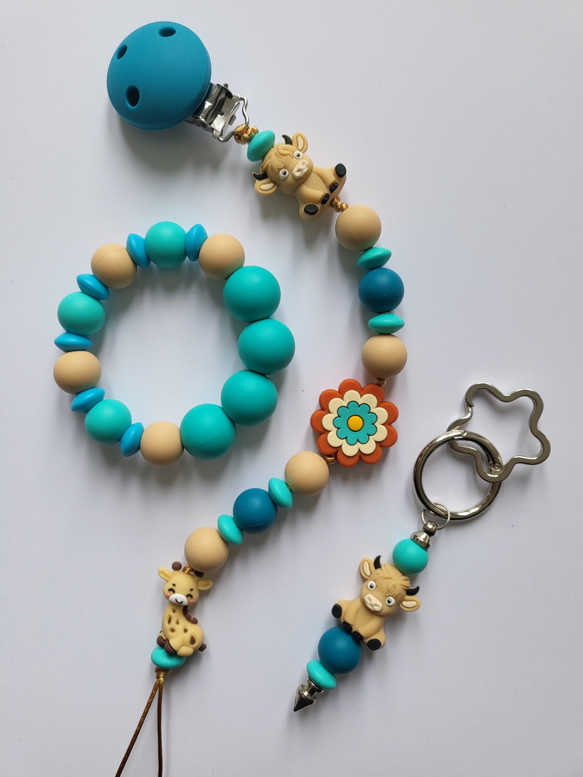 Speenkoord en bijtring met girafje en koetje in petrol-blauw, beige en turquoise.