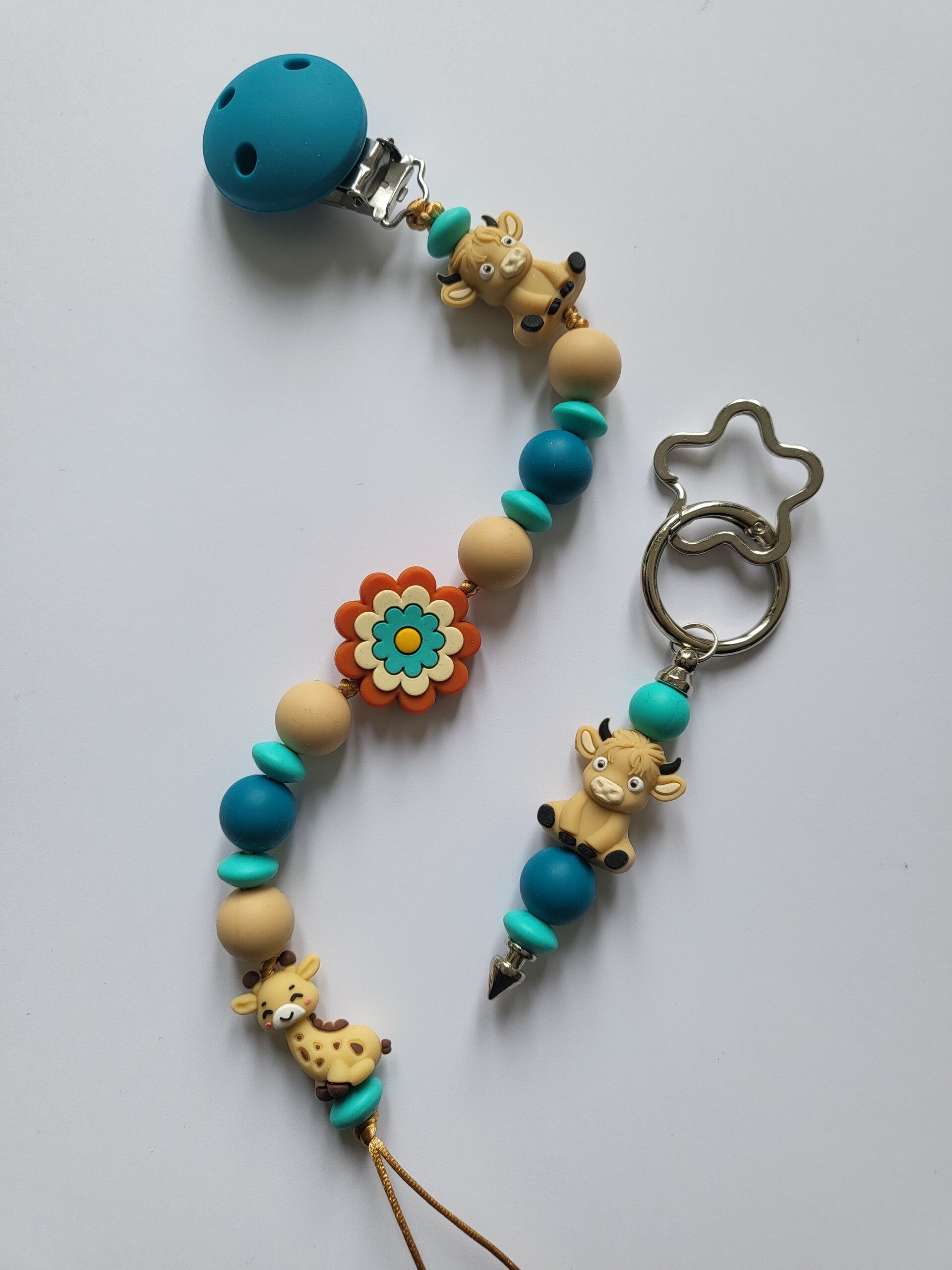 Speenkoord met girafje en koetje in petrol-blauw, beige en turquoise.