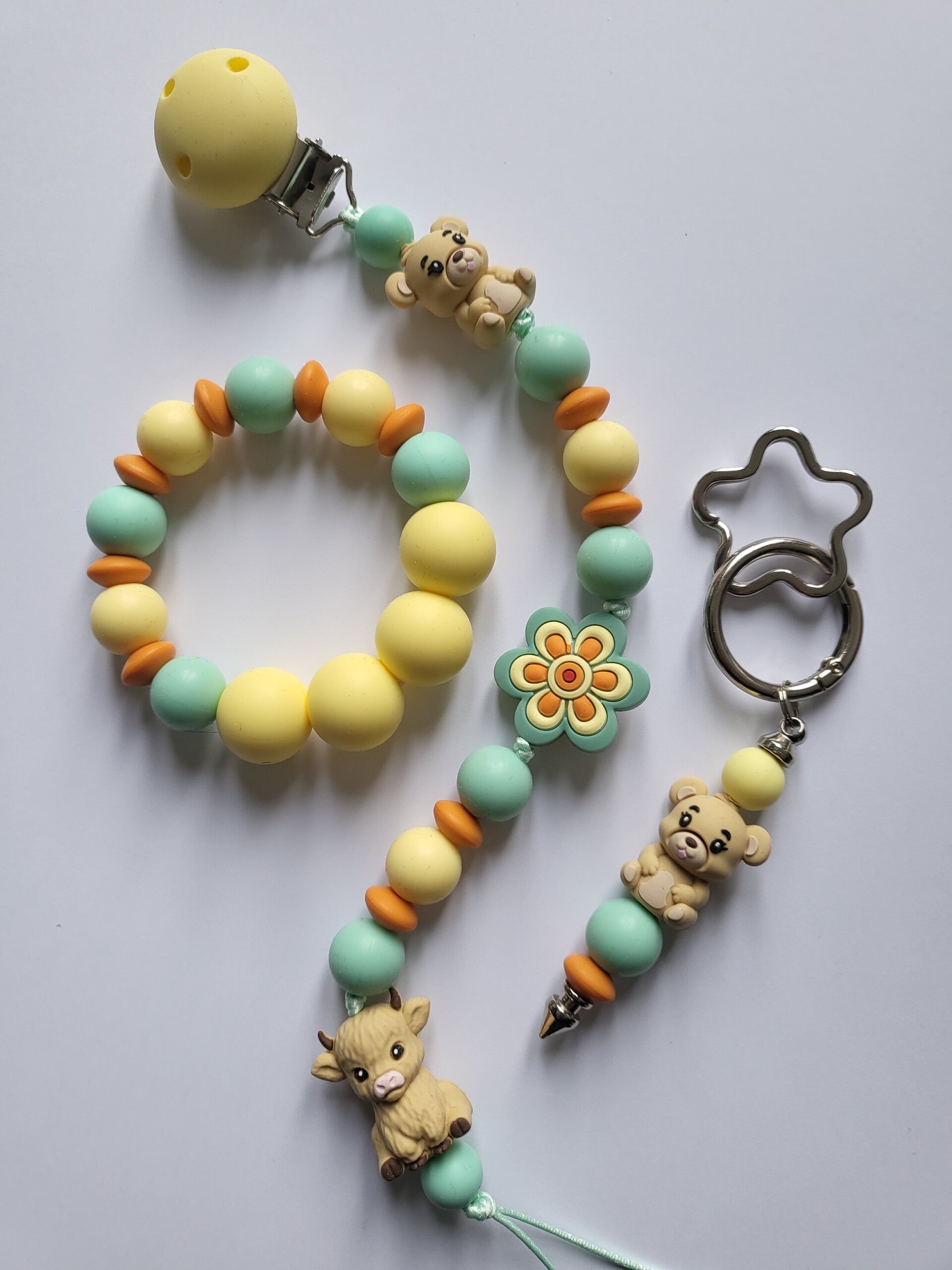 Speenkoord en bijtring met koetje en beertje in lichtgeel, mintgroen, oranje en beige.