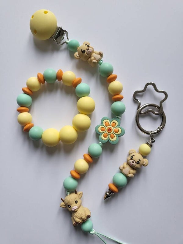 Speenkoord en bijtring met koetje en beertje in lichtgeel, mintgroen, oranje en beige.
