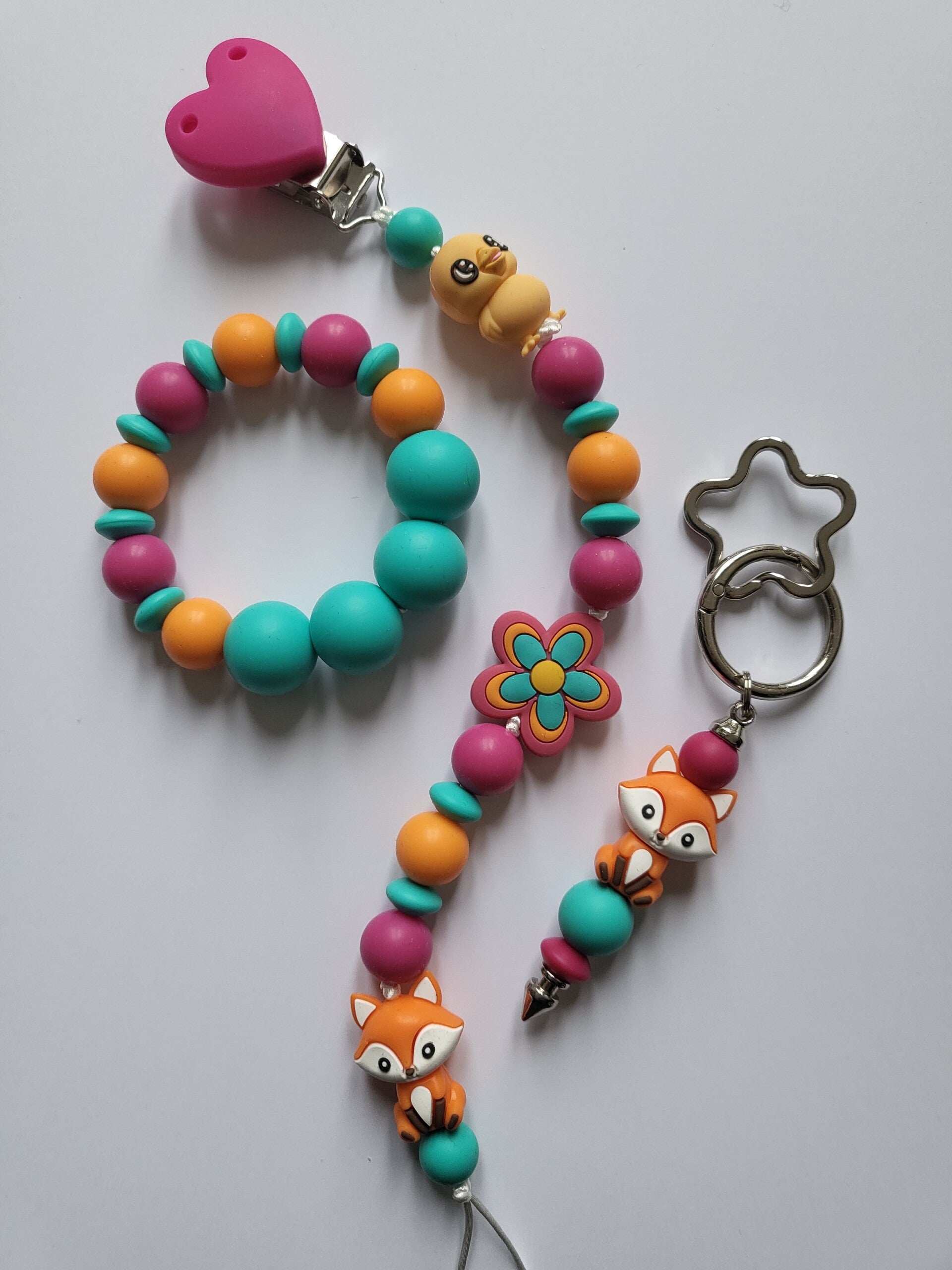 Speenkoord en bijtring met kuikentje en vosje in fuchsia-roze, oranje en turquoise.