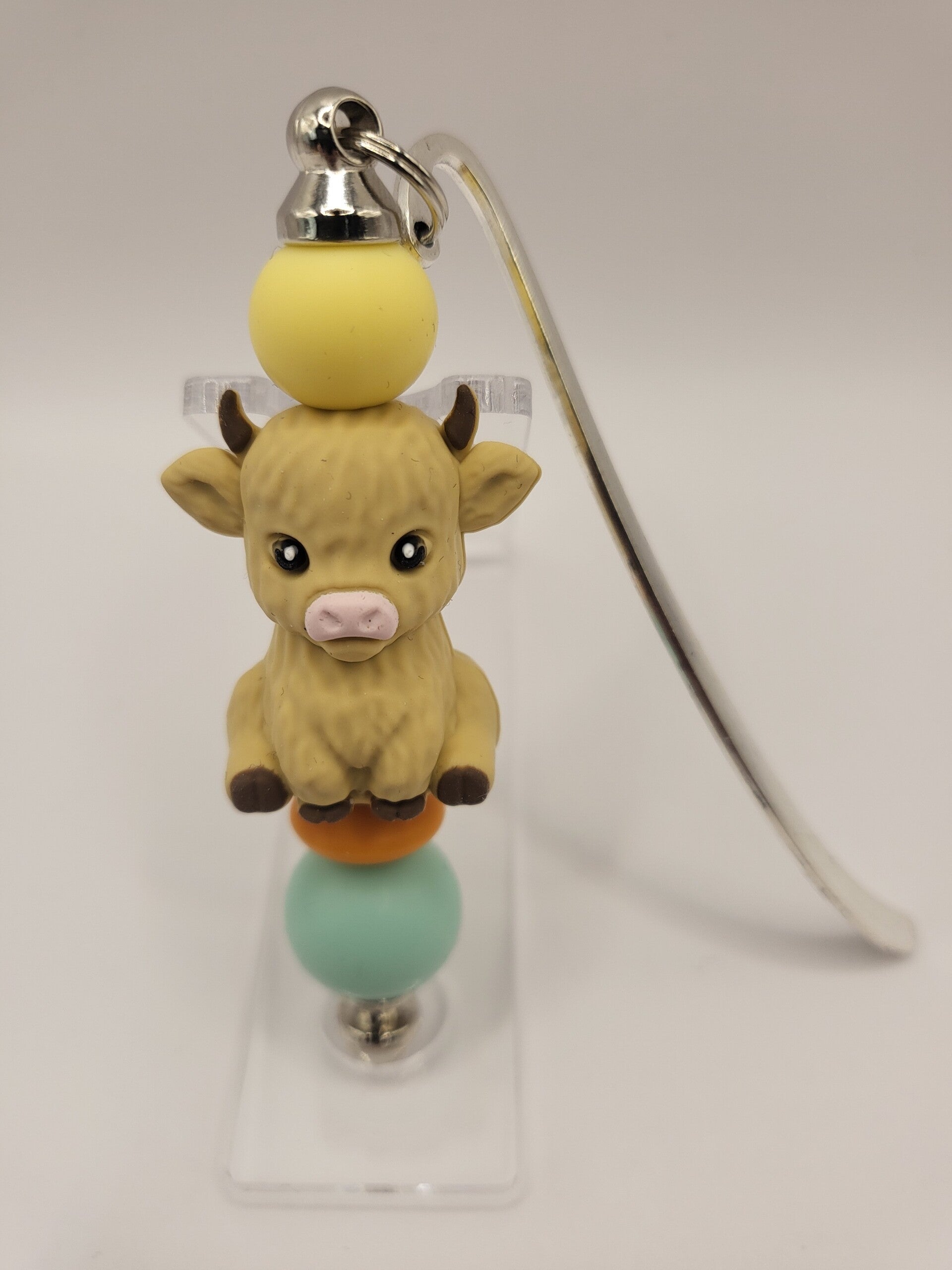 Boekenlegger met koetje in licht-geel, mintgroen, oranje en beige.