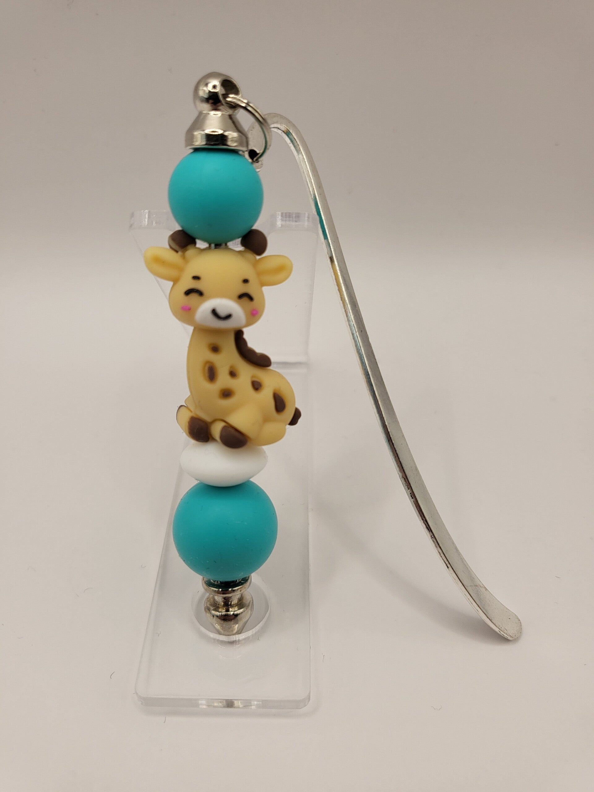 Boekenlegger met girafje in petrol-blauw, beige en turquoise.
