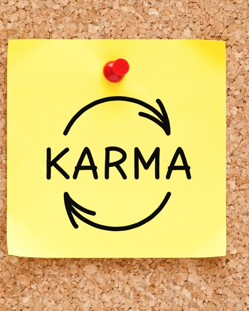cartel amarillo con la palabra karma y un simbolo de ciclo representado por la ley de causa y efecto de los patrones energeticos delalma