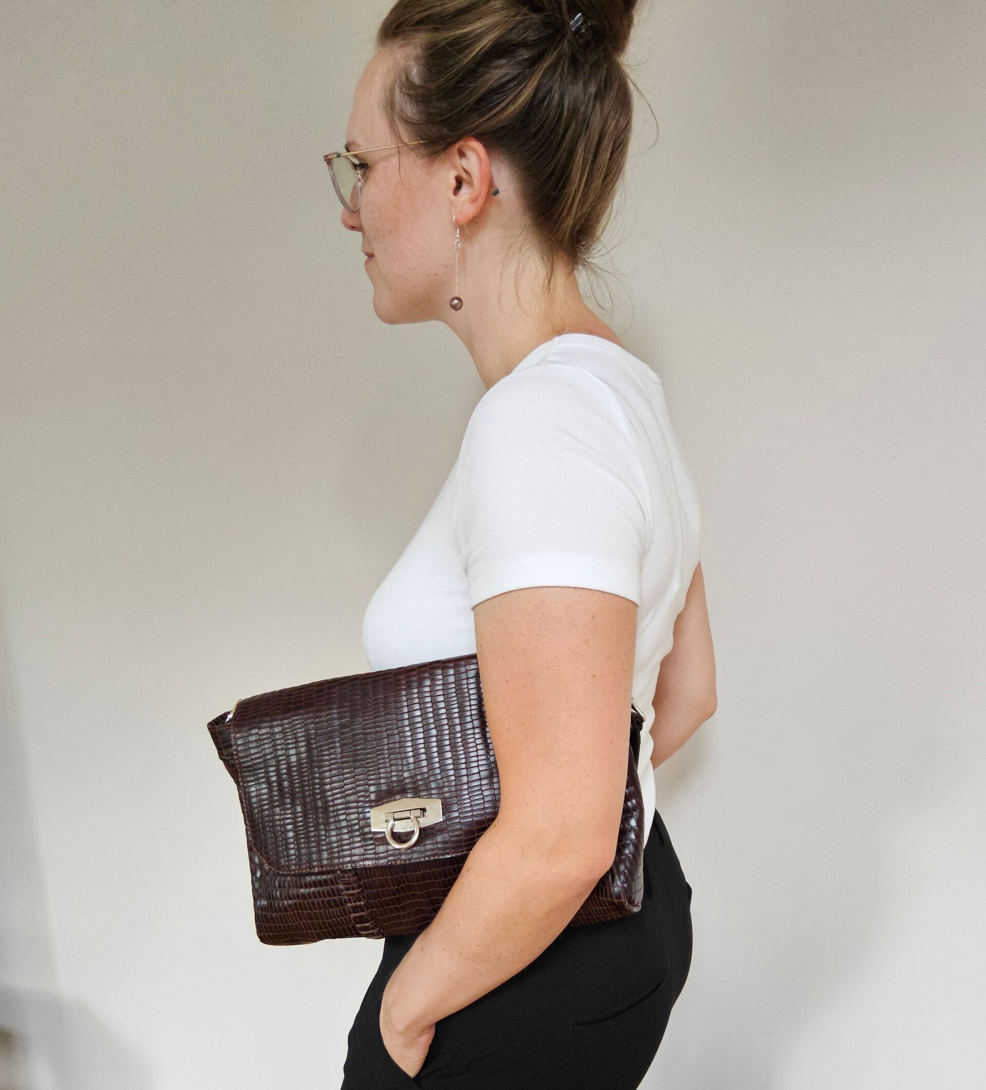 Frau mit Handtasche , braunem Leder Reptilienprägung und silbernem Verschluss