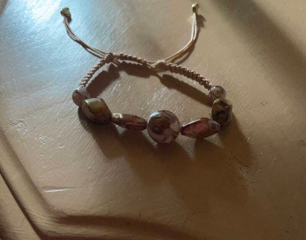 pulsera de hilo en nudo con una bola blanca y brown