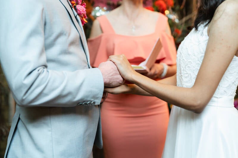 Trouwceremonie. Elvira Patelias, ceremoniespreker, Wedding and Dreams, houdt haar toespraak terwijl het bruidspaar elkaars handen vasthoudt. Een tropische bruiloft in Nederland!  De Jungle Dome in Center parcs Heijderbos is een geweldige trouwlocatie. 