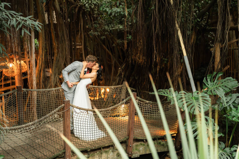 Bruidspaar staat op een bruggetje in de Jungle Dome, Center parcs Heijderbos. Leafsum. Wedding and Dreams.