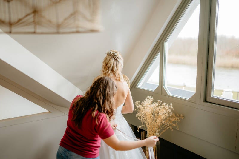 Getting ready. Visagist helpt de bruid met haar bruidsjurk.