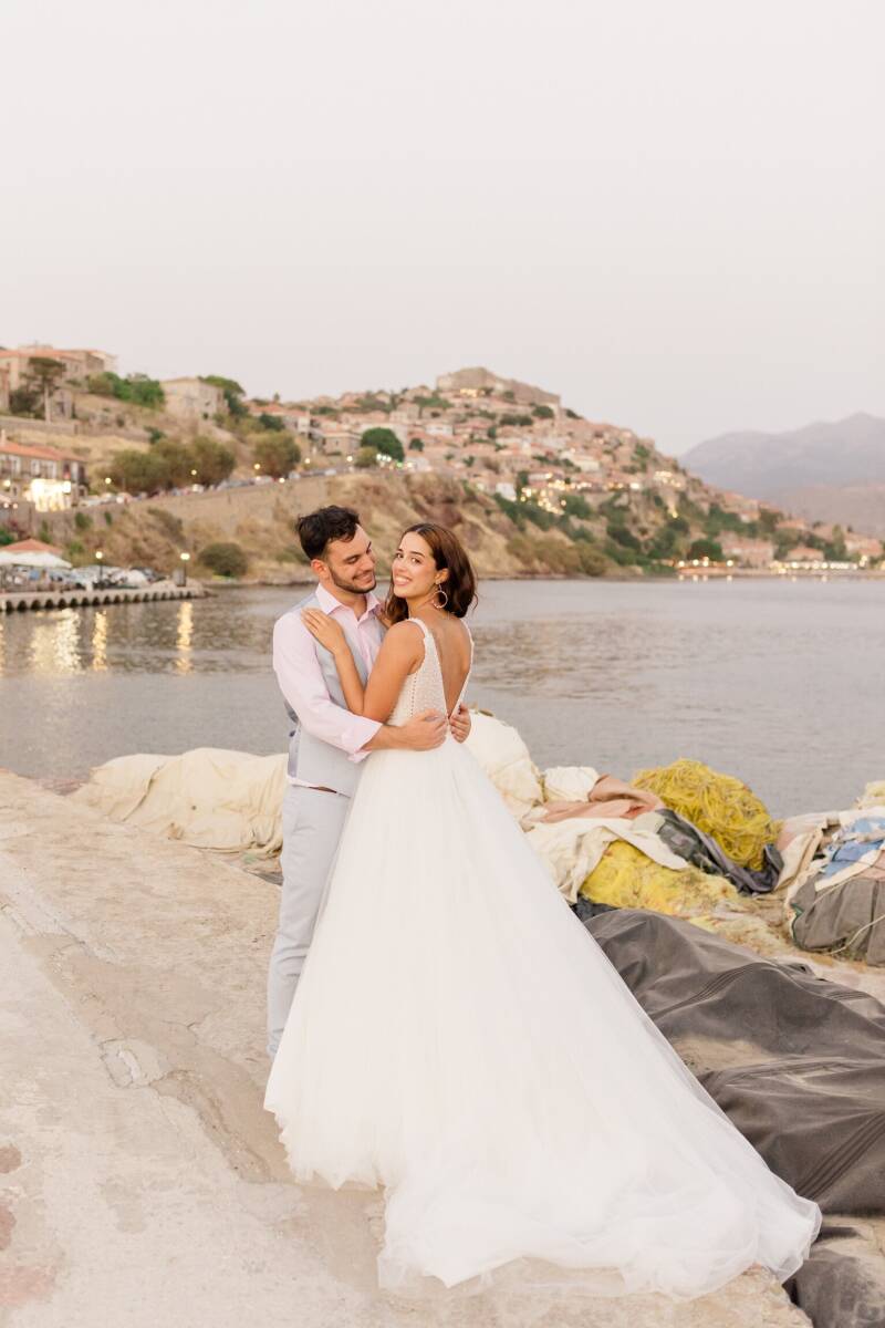 Bruidspaar in het haventje van Molyvos, Lesbos, Griekenland. Op de achtergrond het kasteel en de zee..