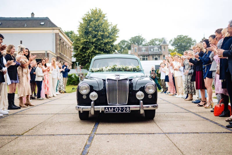 Welkomshaag. Bruid komt aan in de bruidsauto; een prachtige oldtimer, versierd met bloemen.