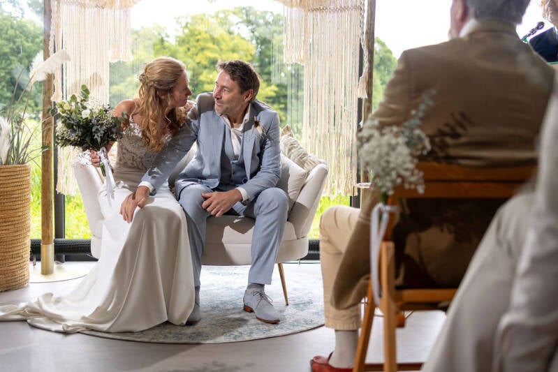 Wenshuwelijk. Het bruidspaar zit op een bankje tijdens de huwelijkscereonie en kijkt elkaar verliefd aan.