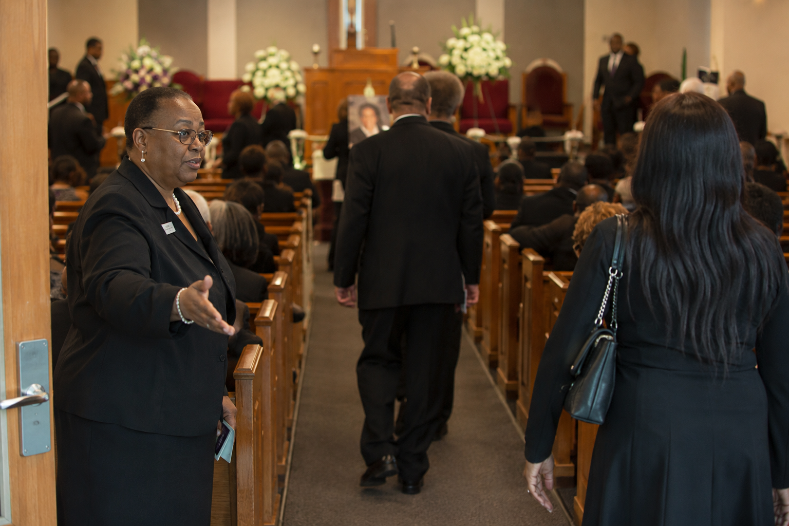 Church funeral coordination team providing guest seating assistance, program distribution, family seating arrangements, clergy support, and congregation guidance during a memorial service in Nairobi, Kenya.
