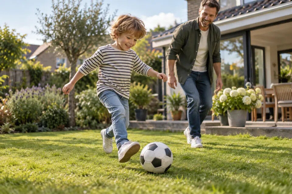 Een kind speelt met een voetbal in een tuin