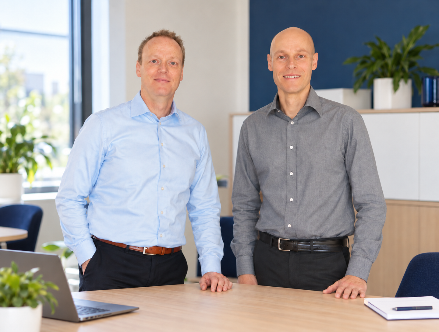 Twee mannen achter een bureau in een lichte kantoorruimte