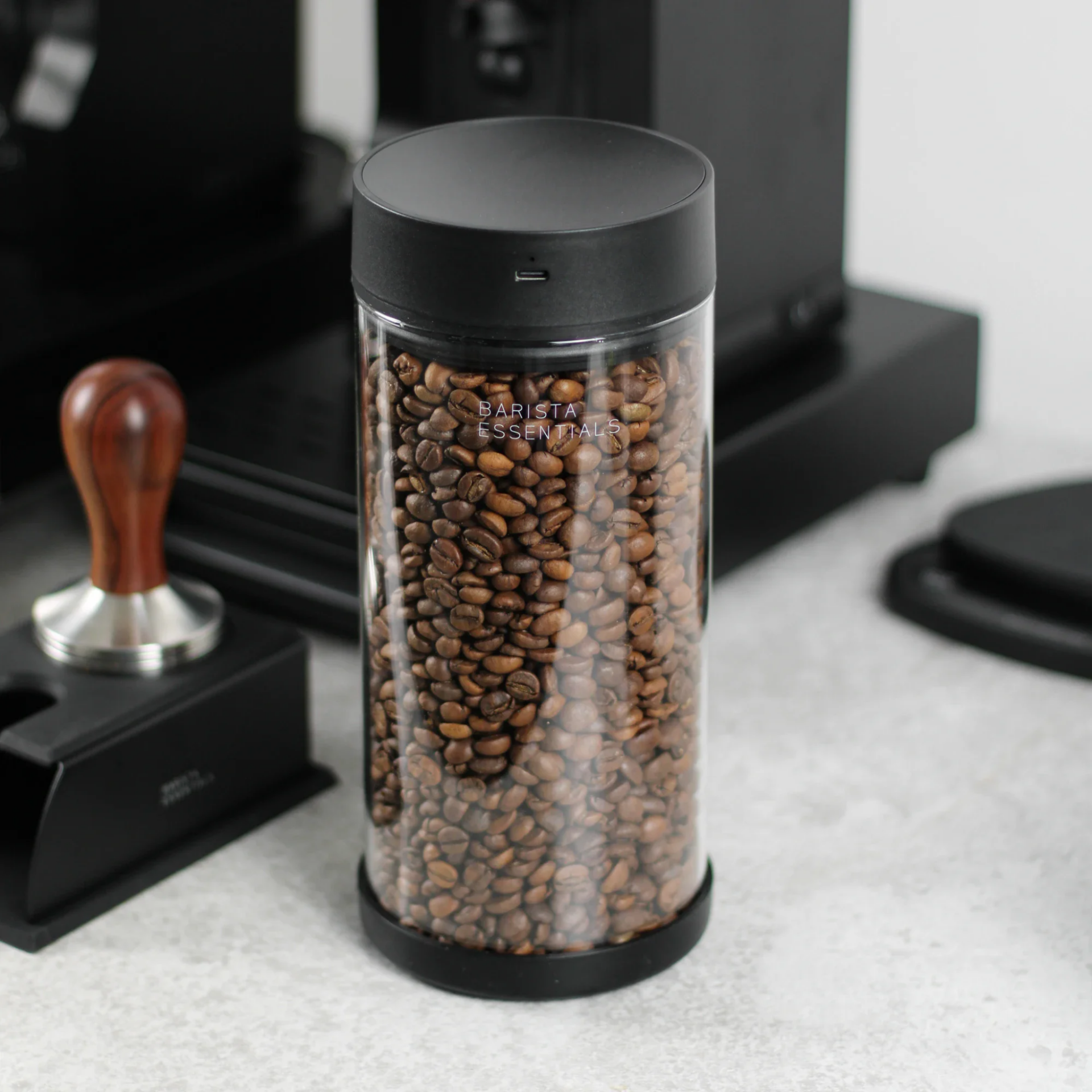 Vacuüm Koffiebus 500g gevuld met vers gebrande koffiebonen, naast espressoset en tamper op een thuisbarista werkblad.