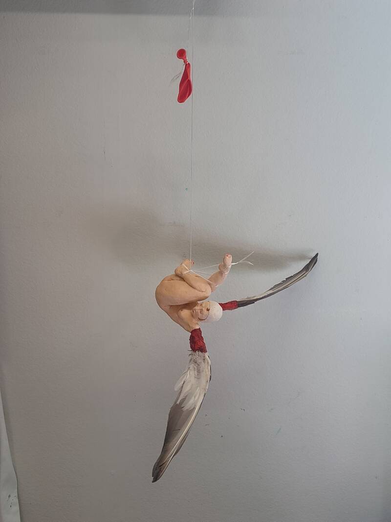 De zus van Icarus (Icarus' sister). 2026. Ceramics, acrylic paint, duck wings, wax, rope, balloon. 15 x 15 x 58 cm.