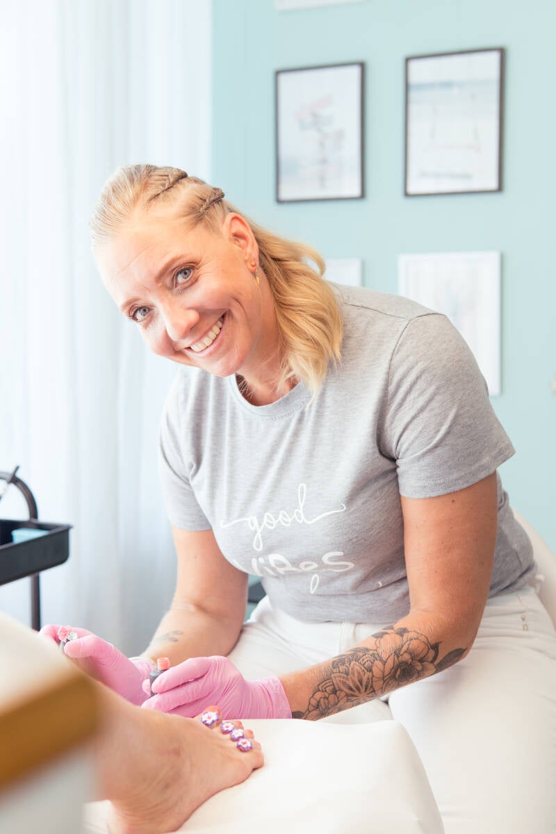 Vrouw lachend (ik) tijdens het lakken van de teennagels.