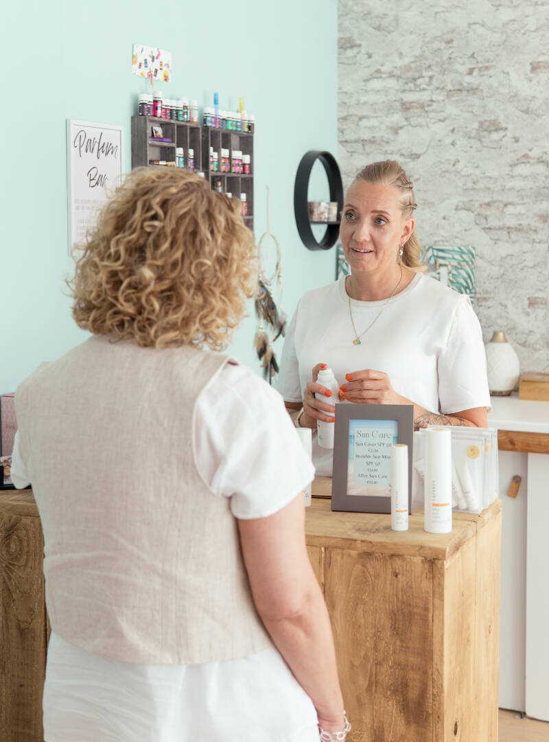 Vrouw ( ik) met klant bij kassa tijdens productadvies
