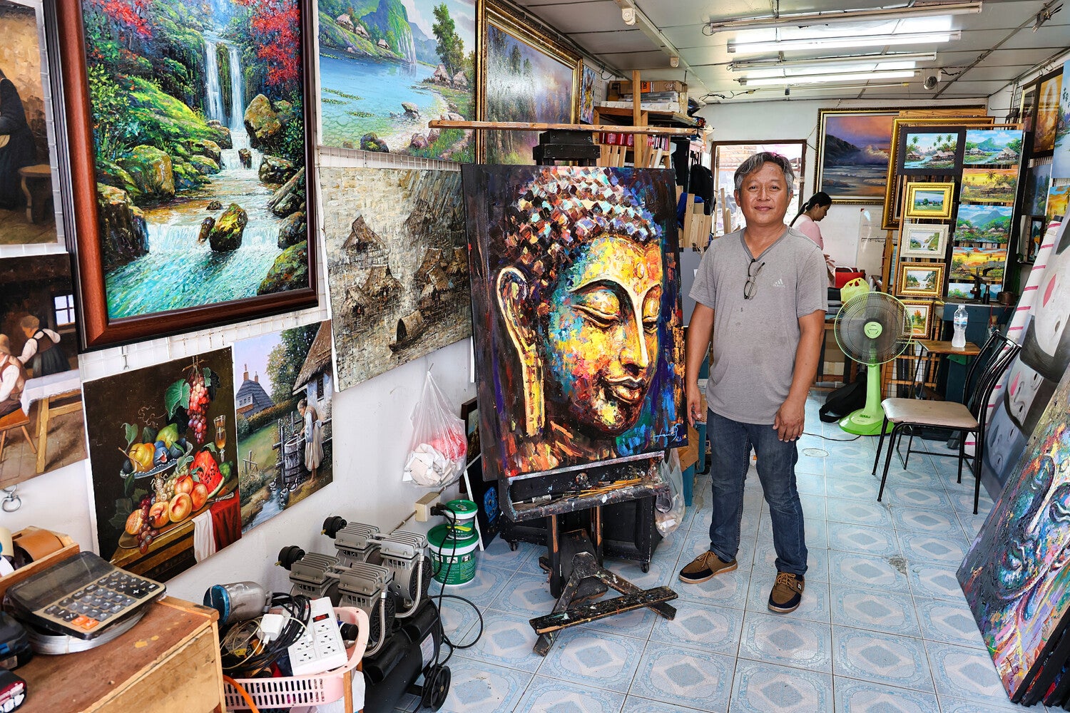 Kunstenaar Seksak Jaichumchen naast Handgeschilderd Boeddha Schilderij Serene Energy in zijn Atelier in Thailand