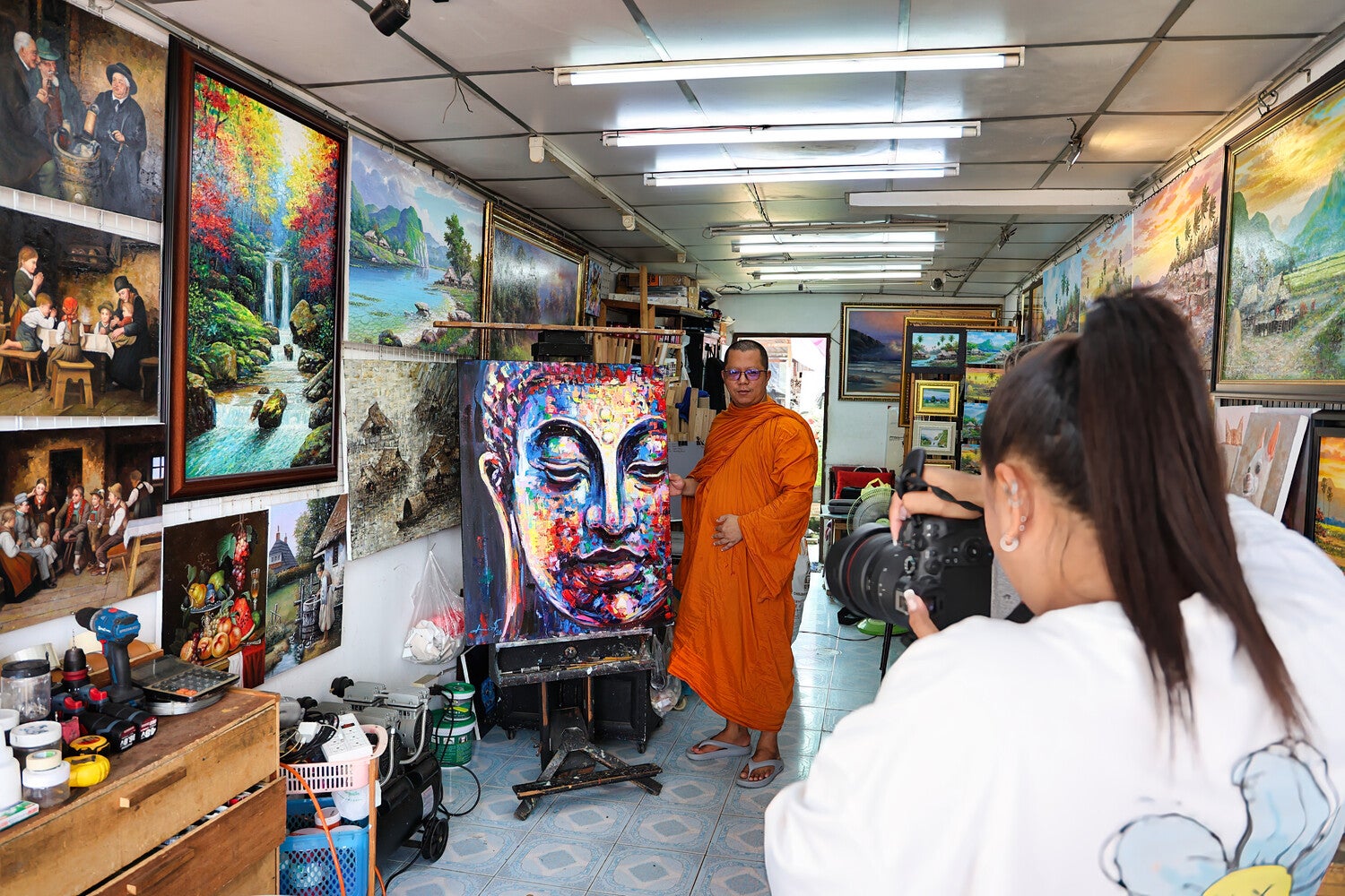 Monnik poseert met handgeschilderd Boeddha schilderij Luminous Peace tijdens fotosessie in atelier Thailand