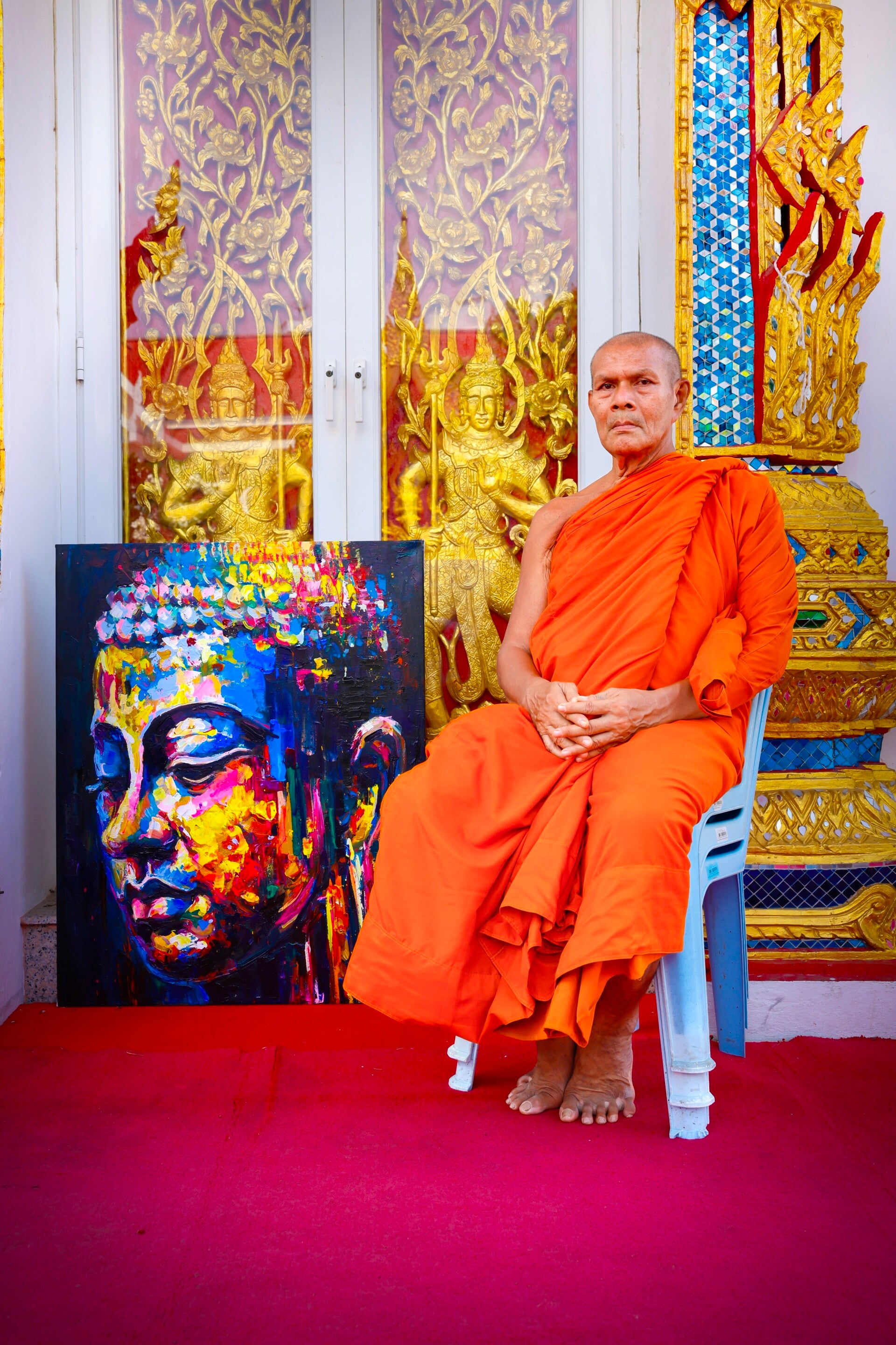 Boeddhistische monnik naast handgeschilderd Boeddha schilderij Energy Flow bij tempel in Thailand