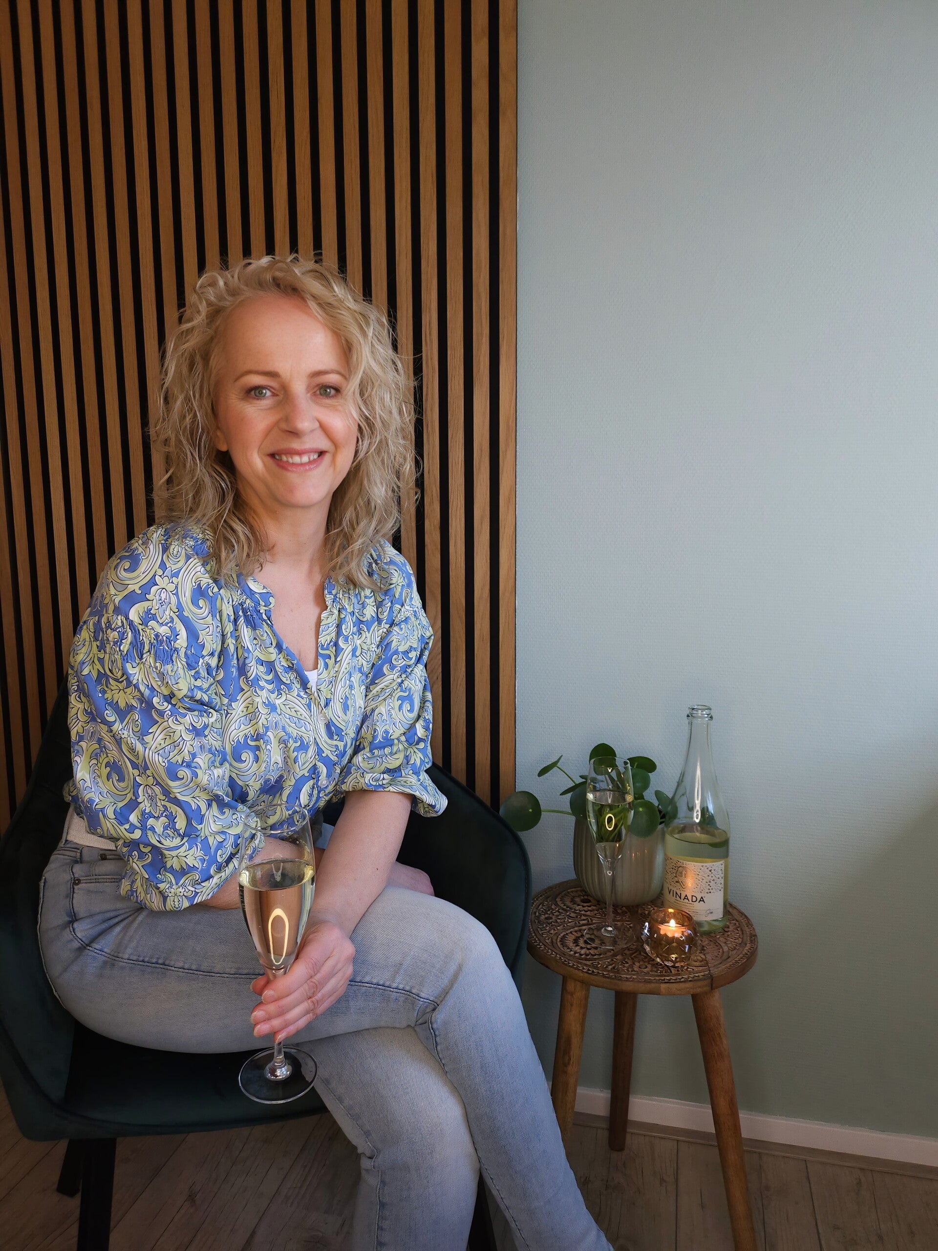 Vrouw staat in een veld en houdt een uitgebloeide paardenbloem vast — symbool voor loslaten en ontspanning in de lente.