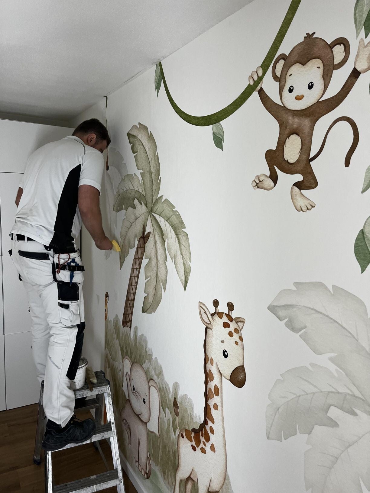 Onze schilder is bezig met het behangen van een kinderkamer