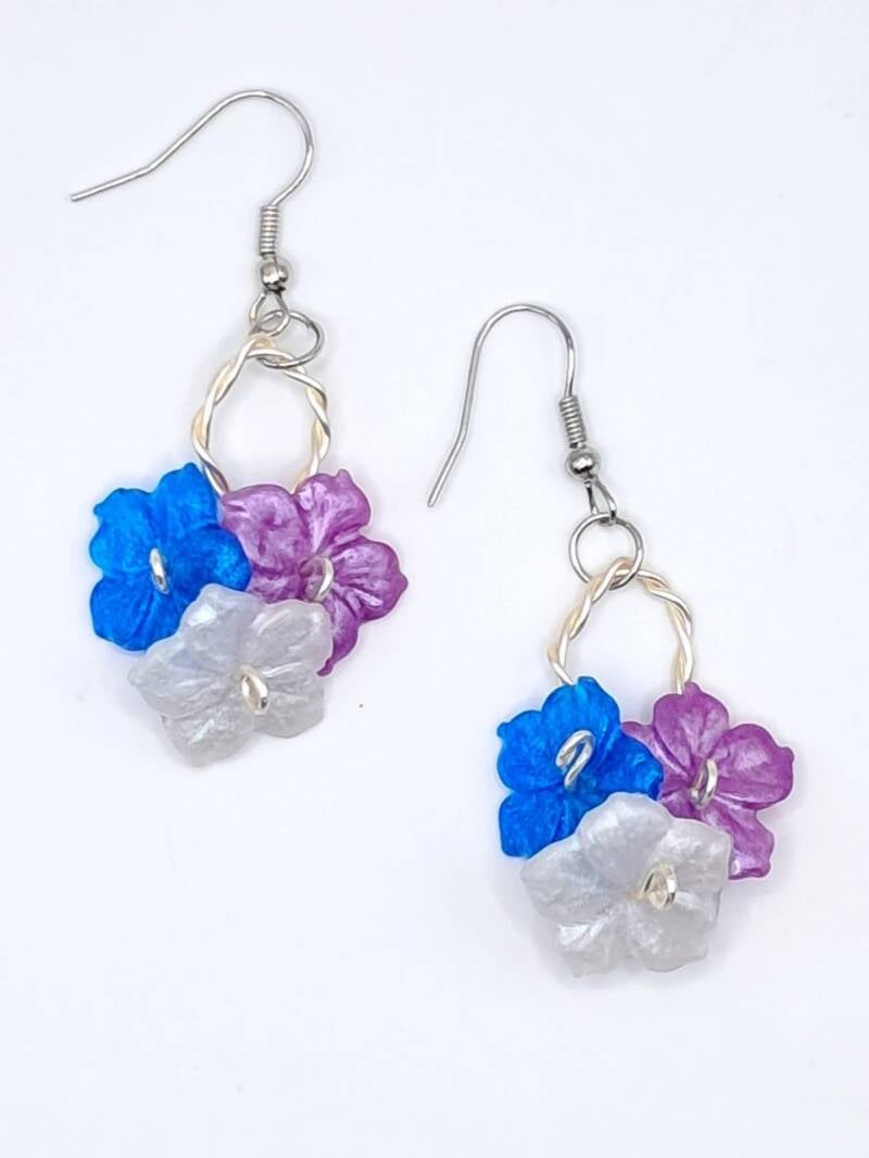 Whimsical, hypoallergenic handmade dangle earrings featuring vibrant resin flower clusters on twisted wire hoops.  Price 20€