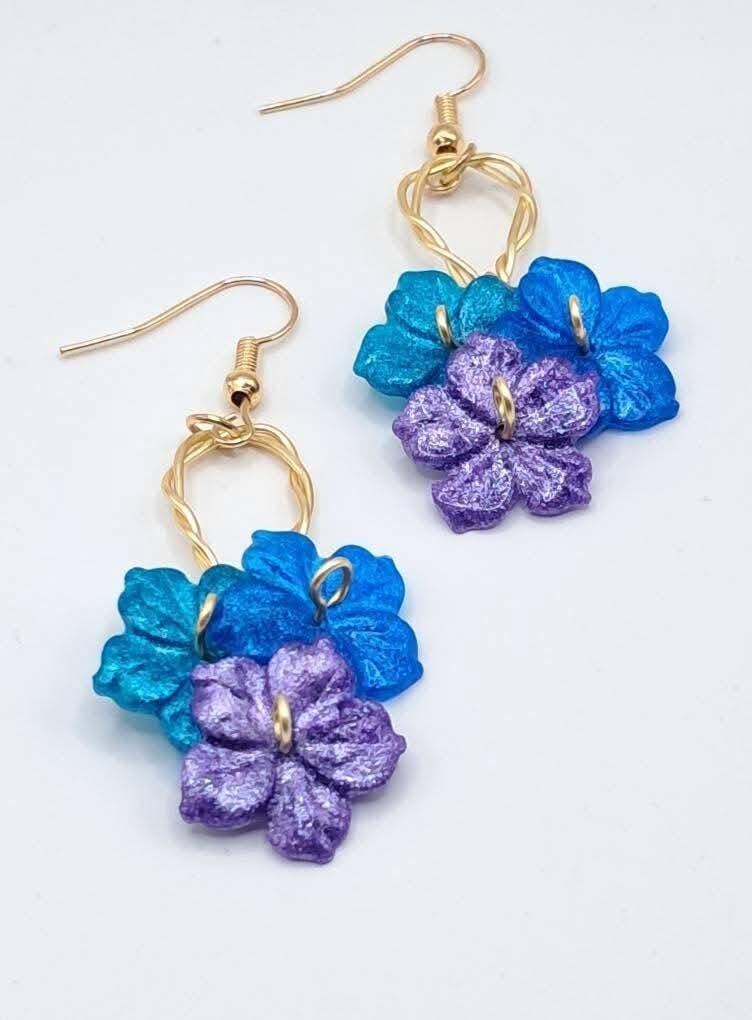 Whimsical, hypoallergenic handmade dangle earrings featuring vibrant resin flower clusters on twisted wire hoops.  Price 20€
