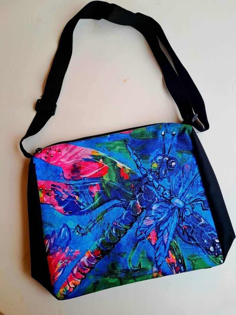 Vibrant, durable satchel bag with  dragonfly art print, adjustable strap, and secure zipper (28 × 30 × 7 cm). Price 30€