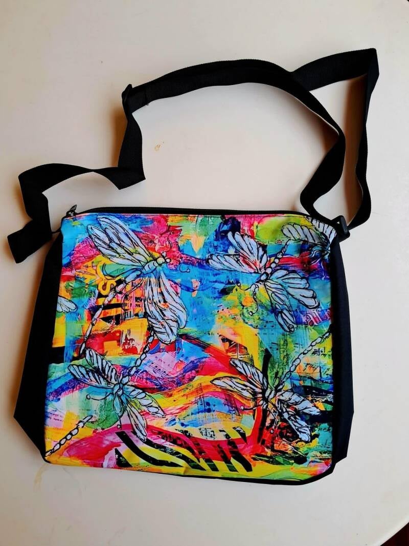 Vibrant, durable satchel bag with  dragonfly art print, adjustable strap, and secure zipper (28 × 30 × 7 cm). Price 30€