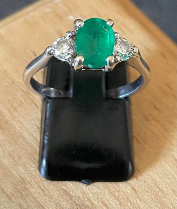 BAGUE EN OR GRIS 750/1000, SERTIE D’UNE EMERAUDE OVALE, ÉPAULEE DE DEUX DIAMANTS D’ENVIRON 0,05 CT CHACUN.