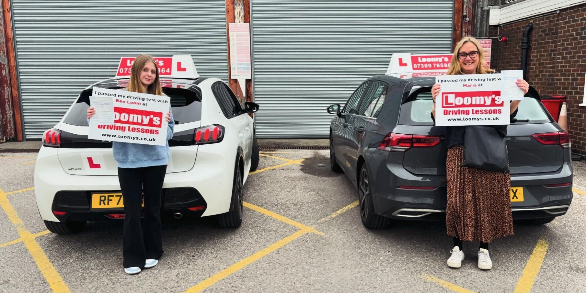 Two successful Loomys learners holding their pass signs beside the driving school cars