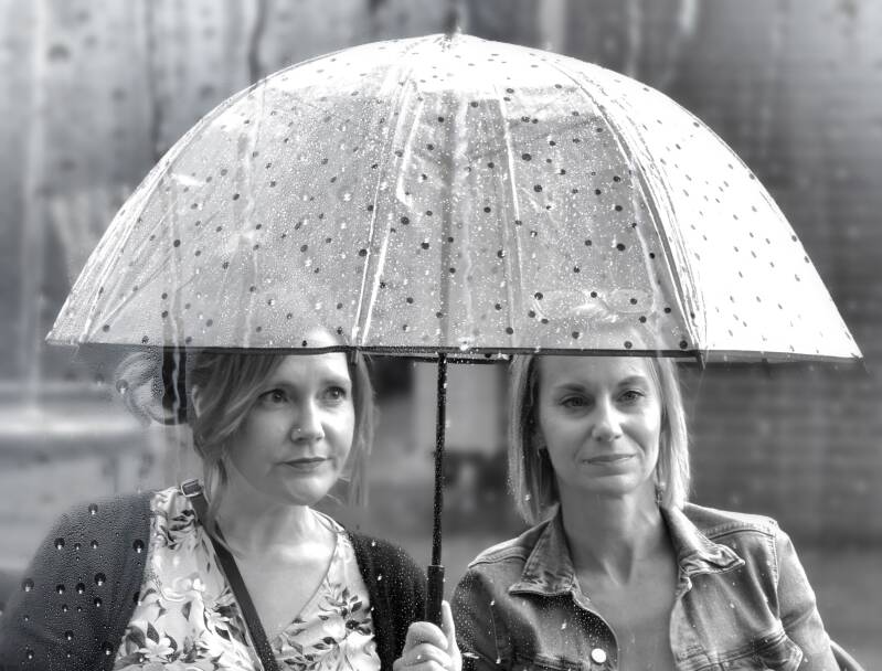 Twee vrouwen onder paraplu in regen – trouwfoto bij slecht weer
