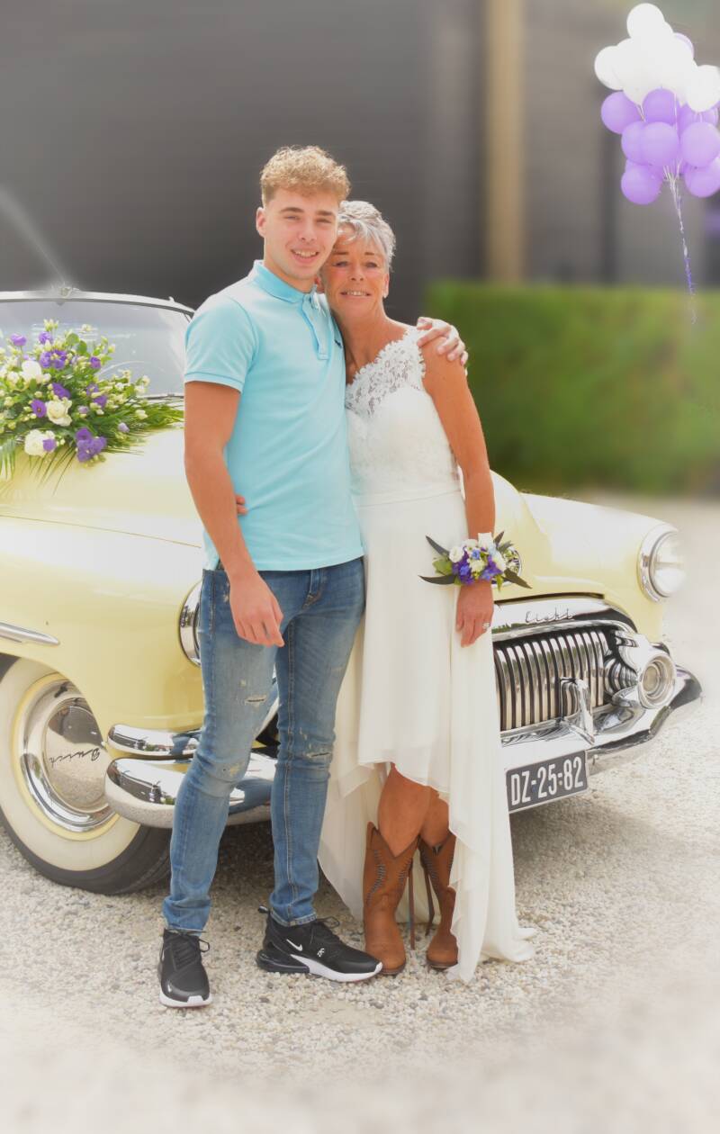 Bruid met bloemen op oldtimer – vrolijke trouwfoto op locatie