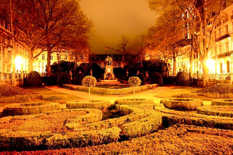 Verlichte stadstuin bij avondlicht – warme kleuren en symmetrische paden