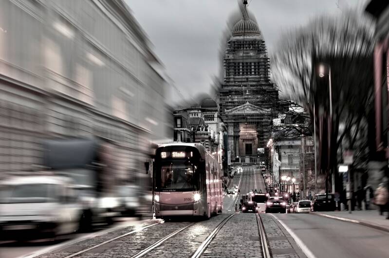 Rijdende tram voor historisch gebouw – stadsdynamiek in zwart-wit