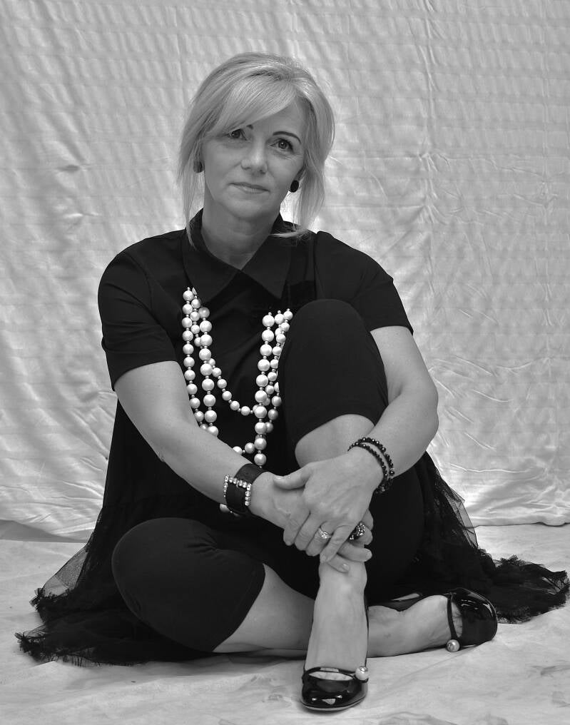 Vrouw zittend voor neutrale achtergrond – zakelijk portret met rustige uitstraling